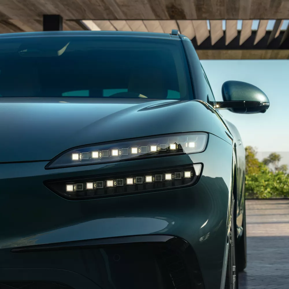 Front angle close up of driver side headlight and grille on Genesis GV60 in Tromso Green