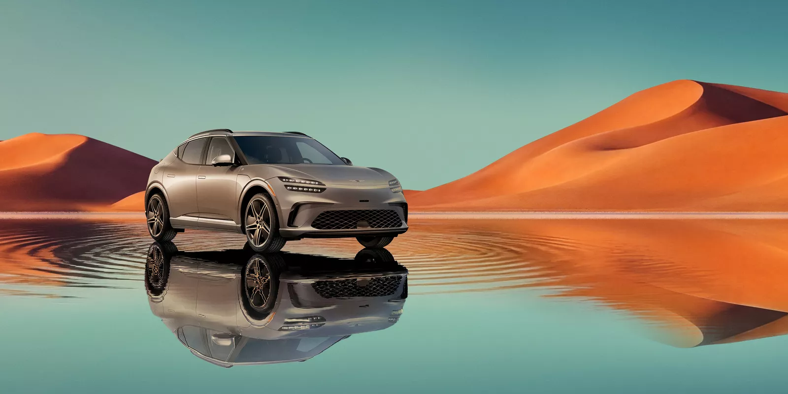 7/8 front passenger view of Savile Silver Genesis GV60 on blue lake w/ orange mountain in background