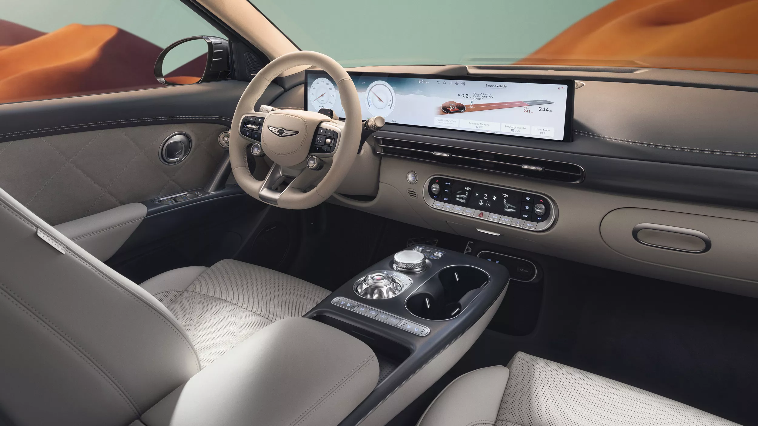 Interior view of gray front seating inside Genesis GV60 with blue sky and mountains in background