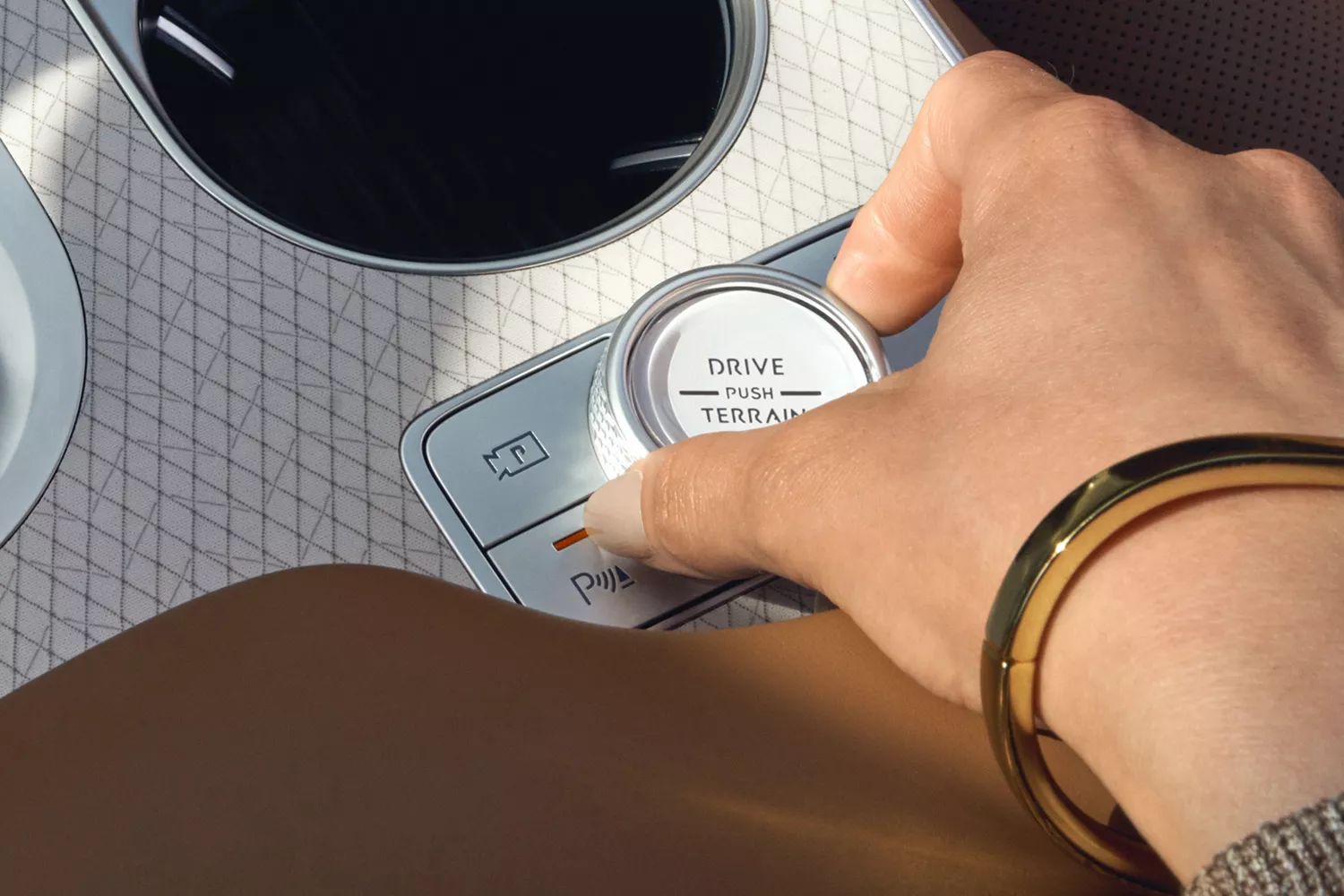 Interior close up of hand placed on shift by wire dial in center console of Genesis GV80