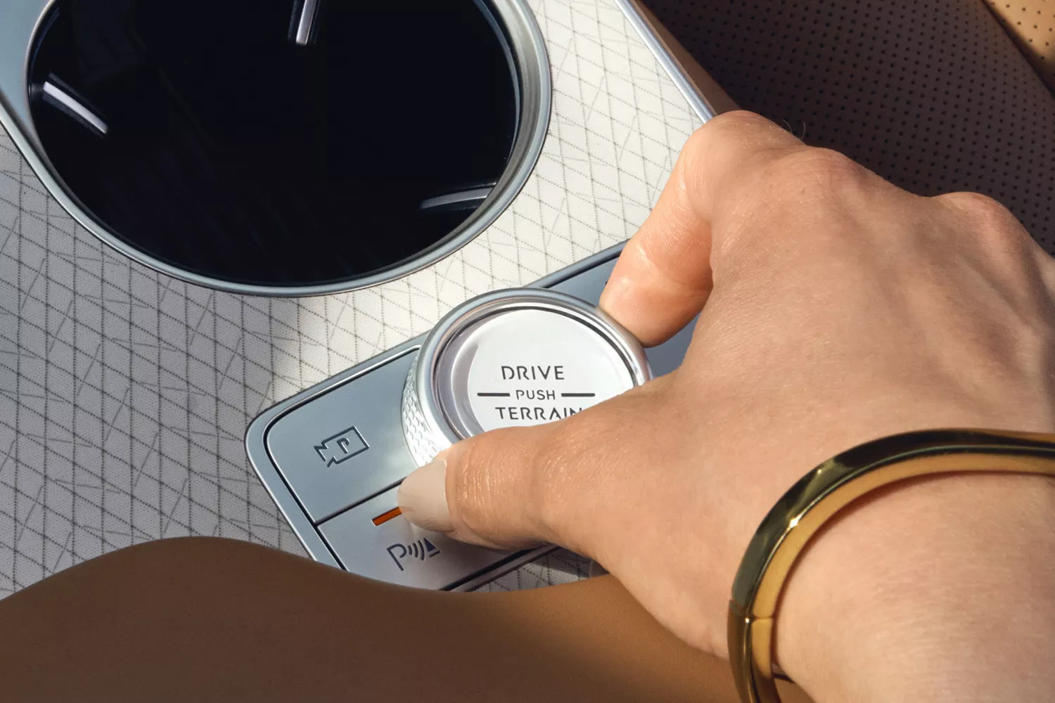 Interior closeup of driver's hand holding Drive Mode dial on center console of Genesis GV80