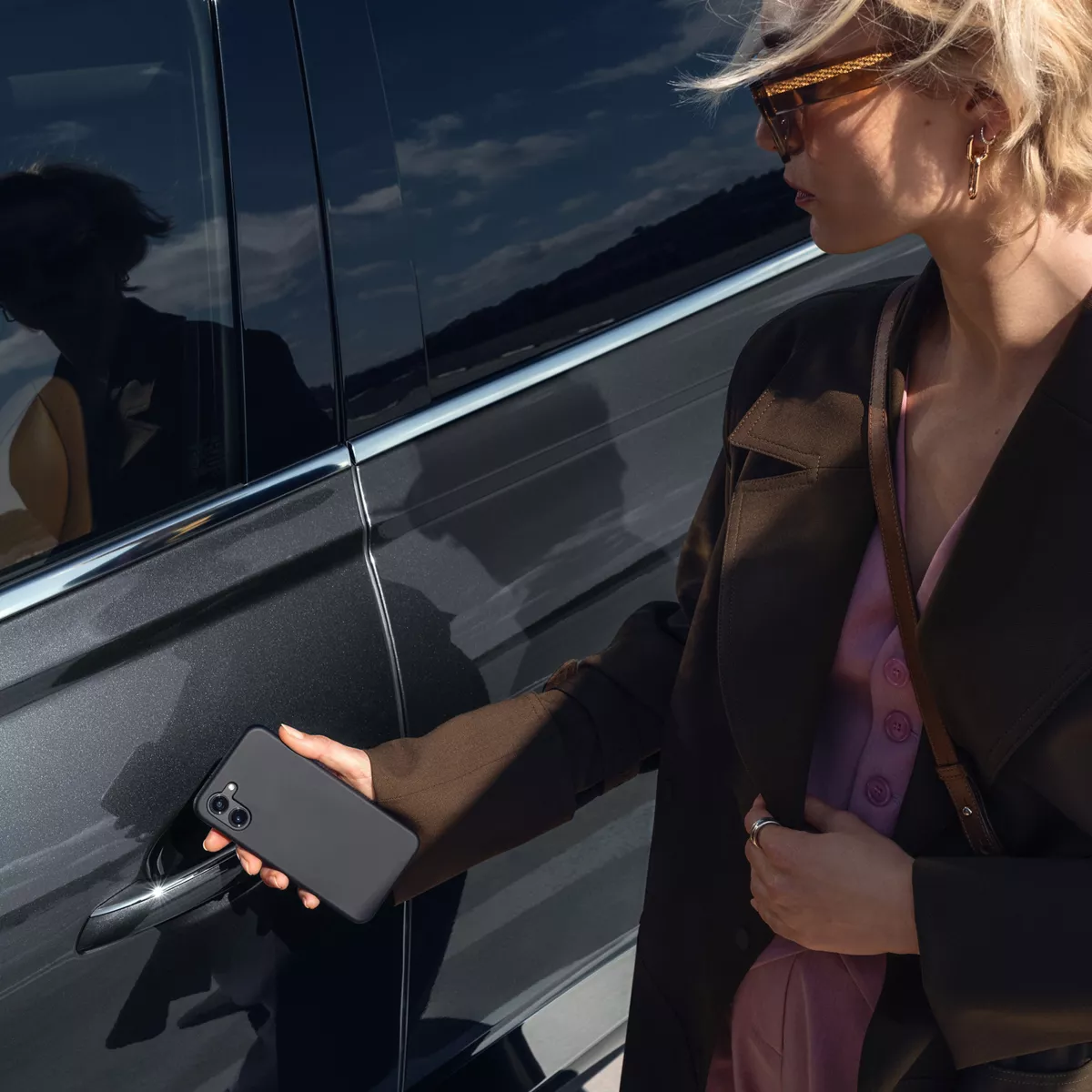 Genesis GV80 driver using digital key on smartphone to unlock vehicle, showcasing connected technology