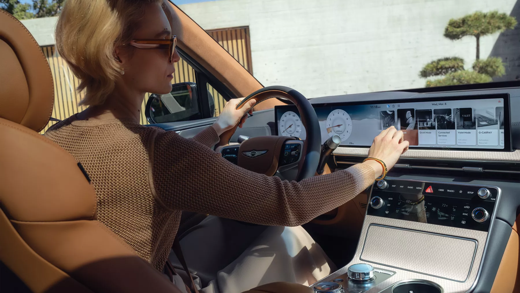 Interior passenger seat pov of driver in Genesis GV80 touching infotainment/navigation screen