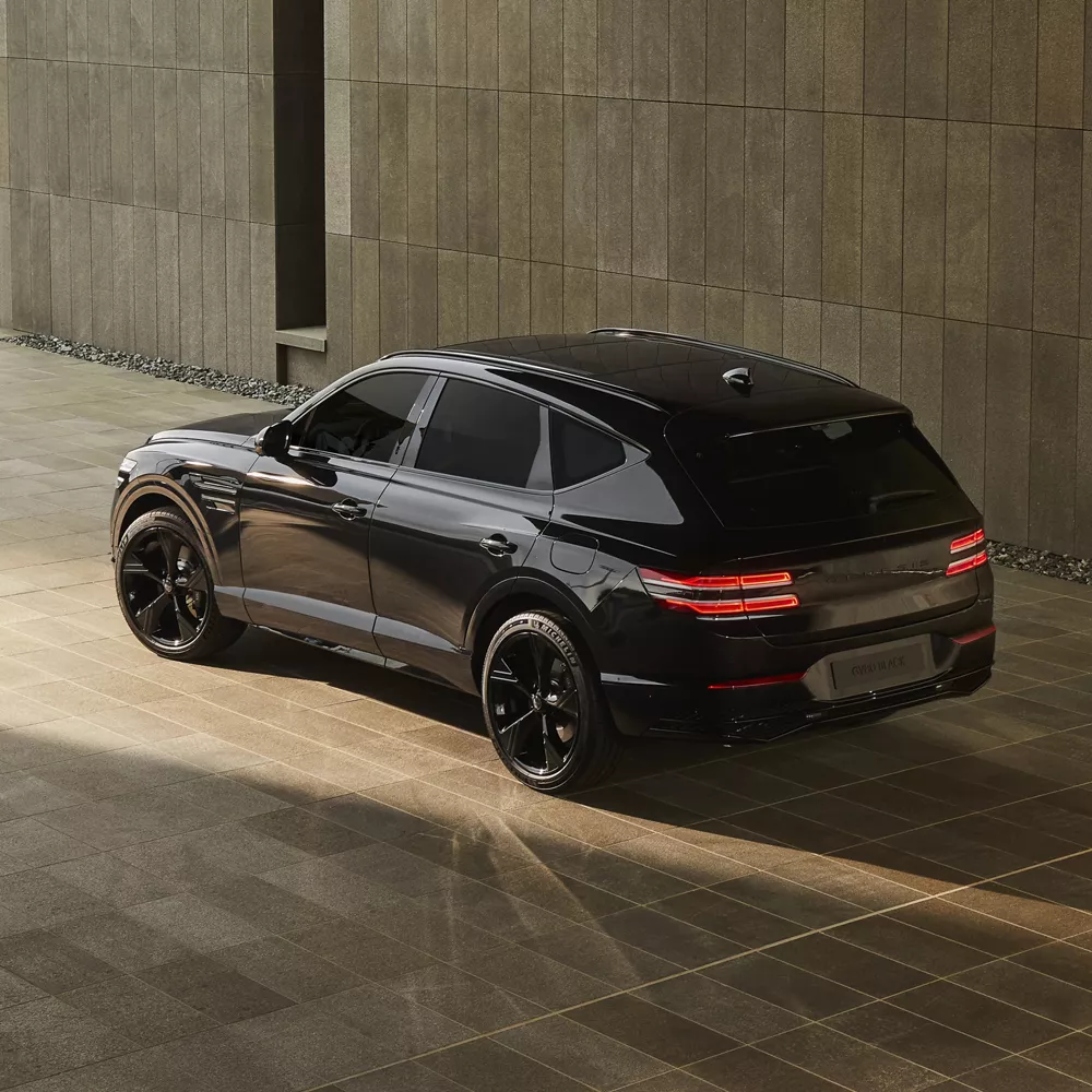 3/4 rear driver side view of Genesis GV80 Prestige Black parked in front of cement structure