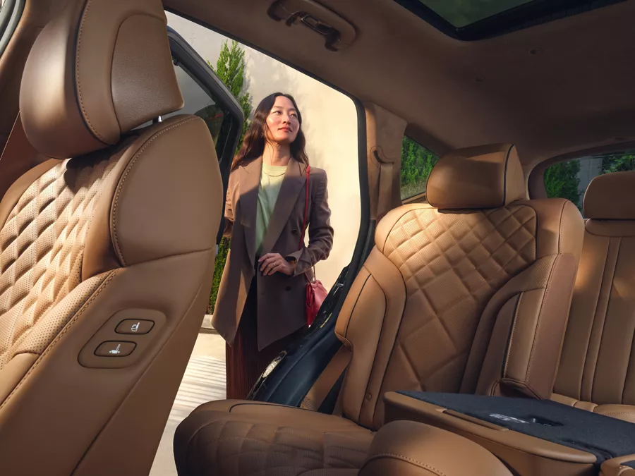 Front driver side POV of Genesis GV80 rear interior with tan quilted leather seats & open rear door