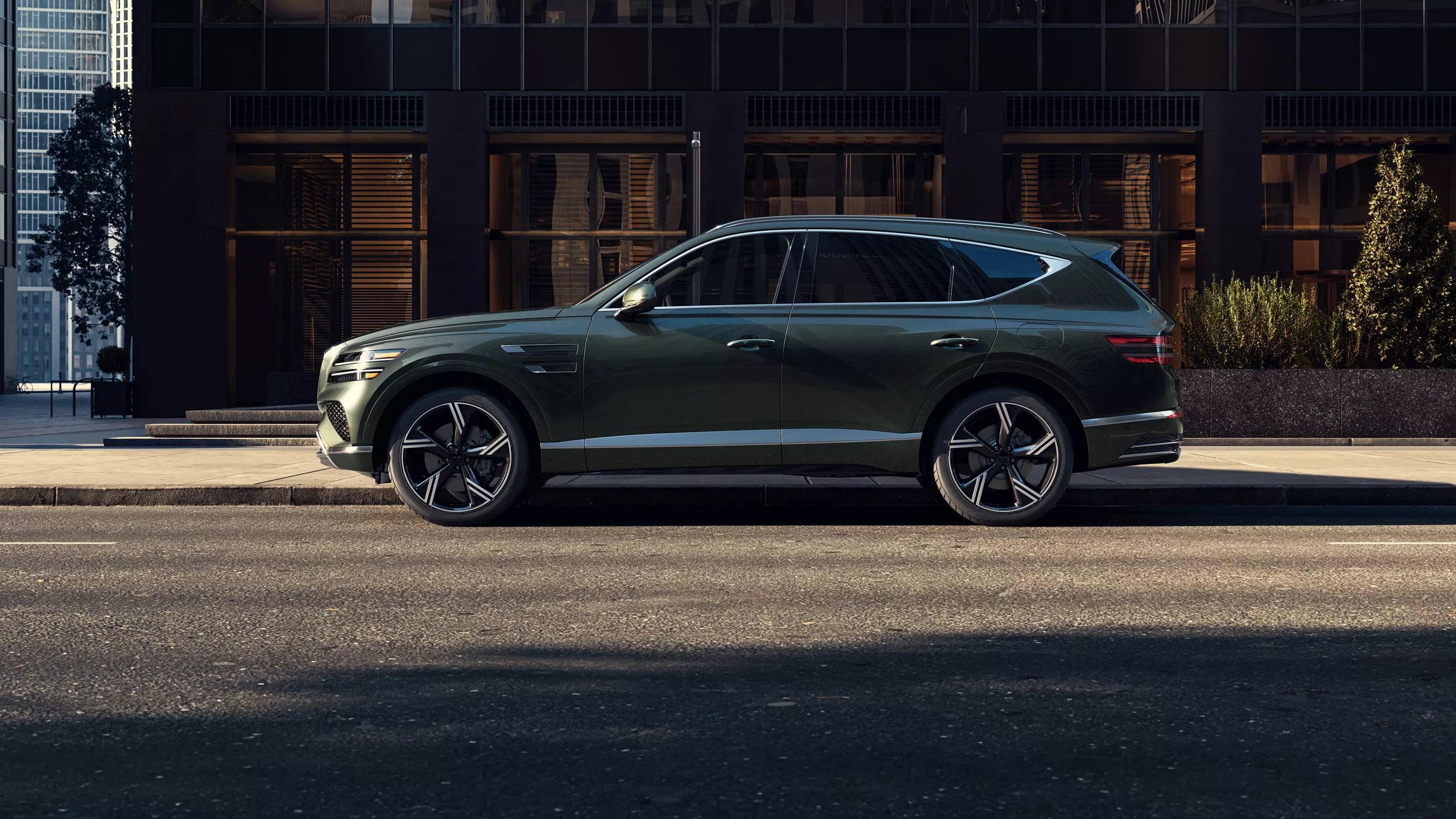 Driver side profile of 2026 Genesis GV80 3.5T Prestige AWD in Storr Green parked on a city street