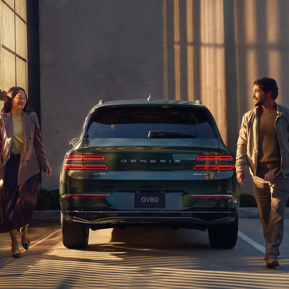 Rear view of Genesis GV80 in Storr Green parked in front of a wall with heavy shadows