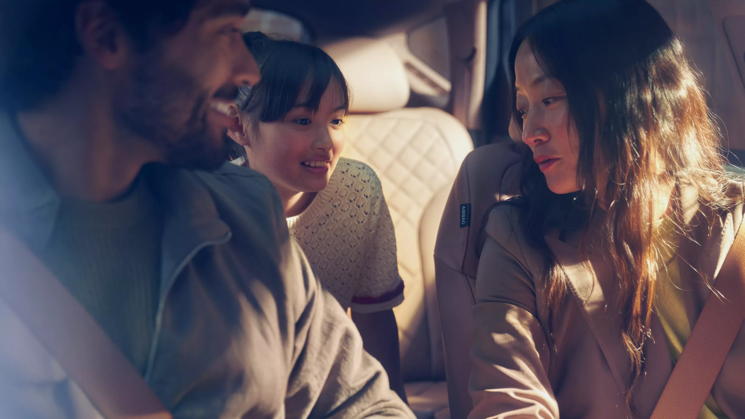 Interior close-up of parents in front seat, child in the backseat, inside Genesis GV80