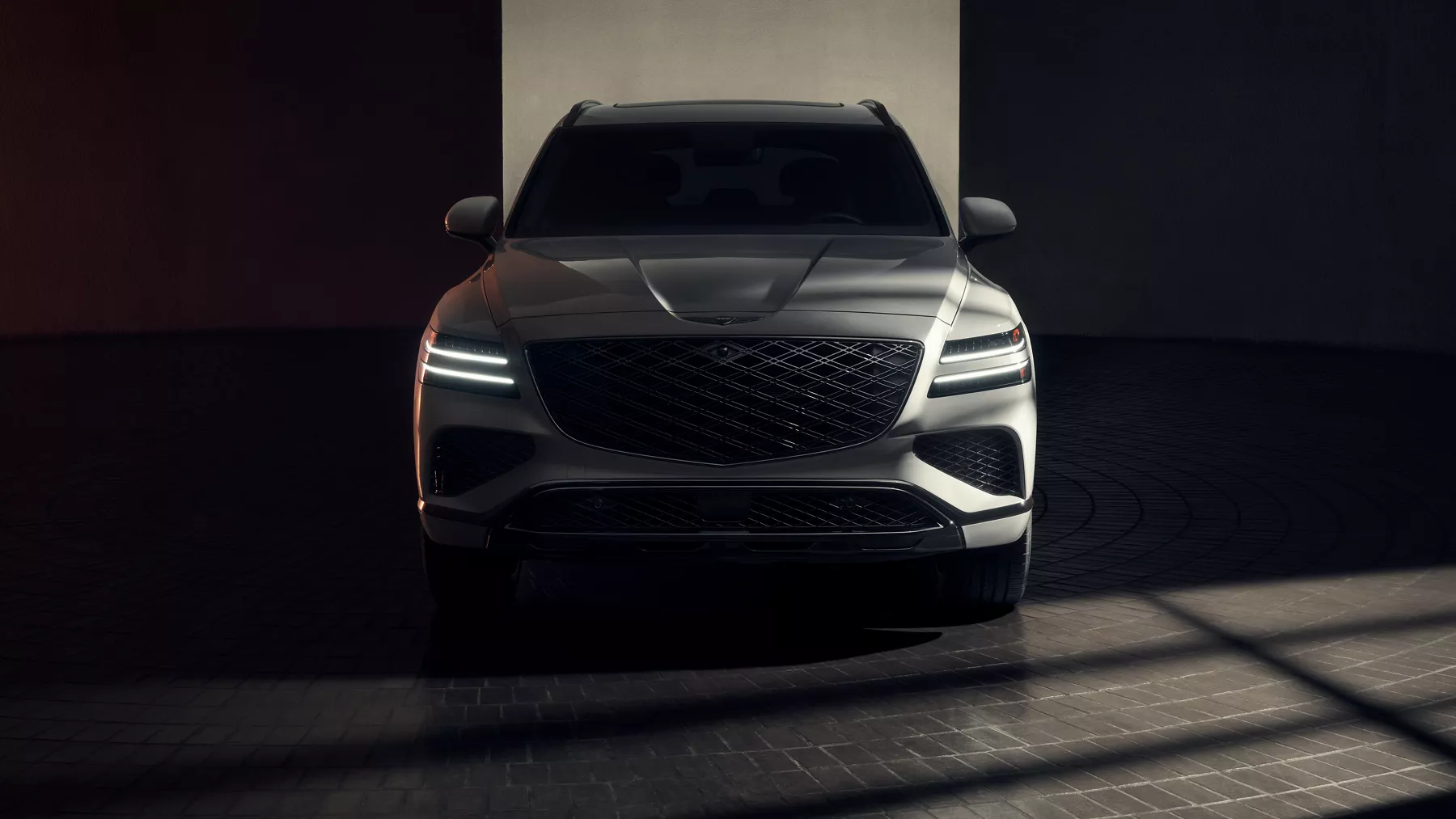 Front facing view of Genesis GV80 Prestige Black in Uyuni White, parked in dimly lit room