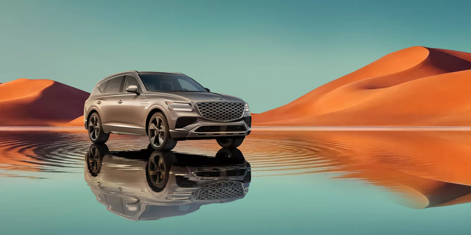 7/8 front passenger view of Savile Silver Genesis GV80 on blue lake w/ orange mountain in background