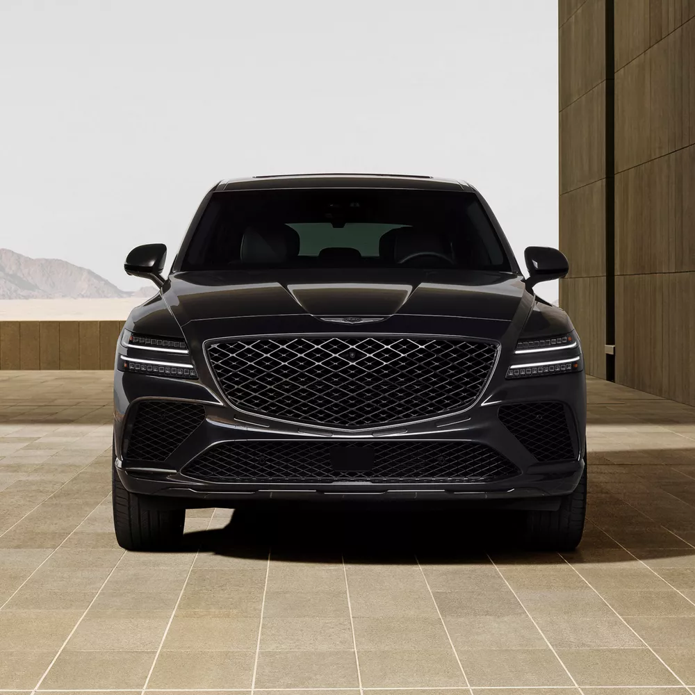 Front facing view of Genesis GV80 Coupe Prestige Black parked in front of modern concrete building