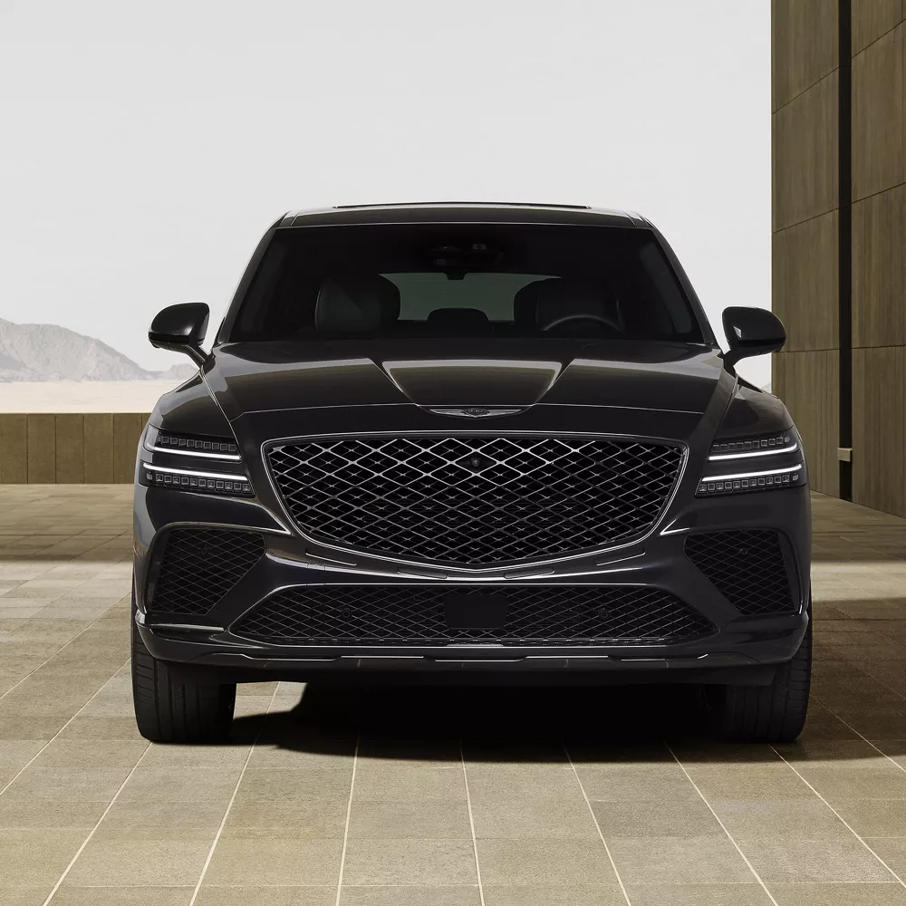 Front view of 2026 Genesis GV80 Coupe Prestige Black parked outside of a modern building in desert