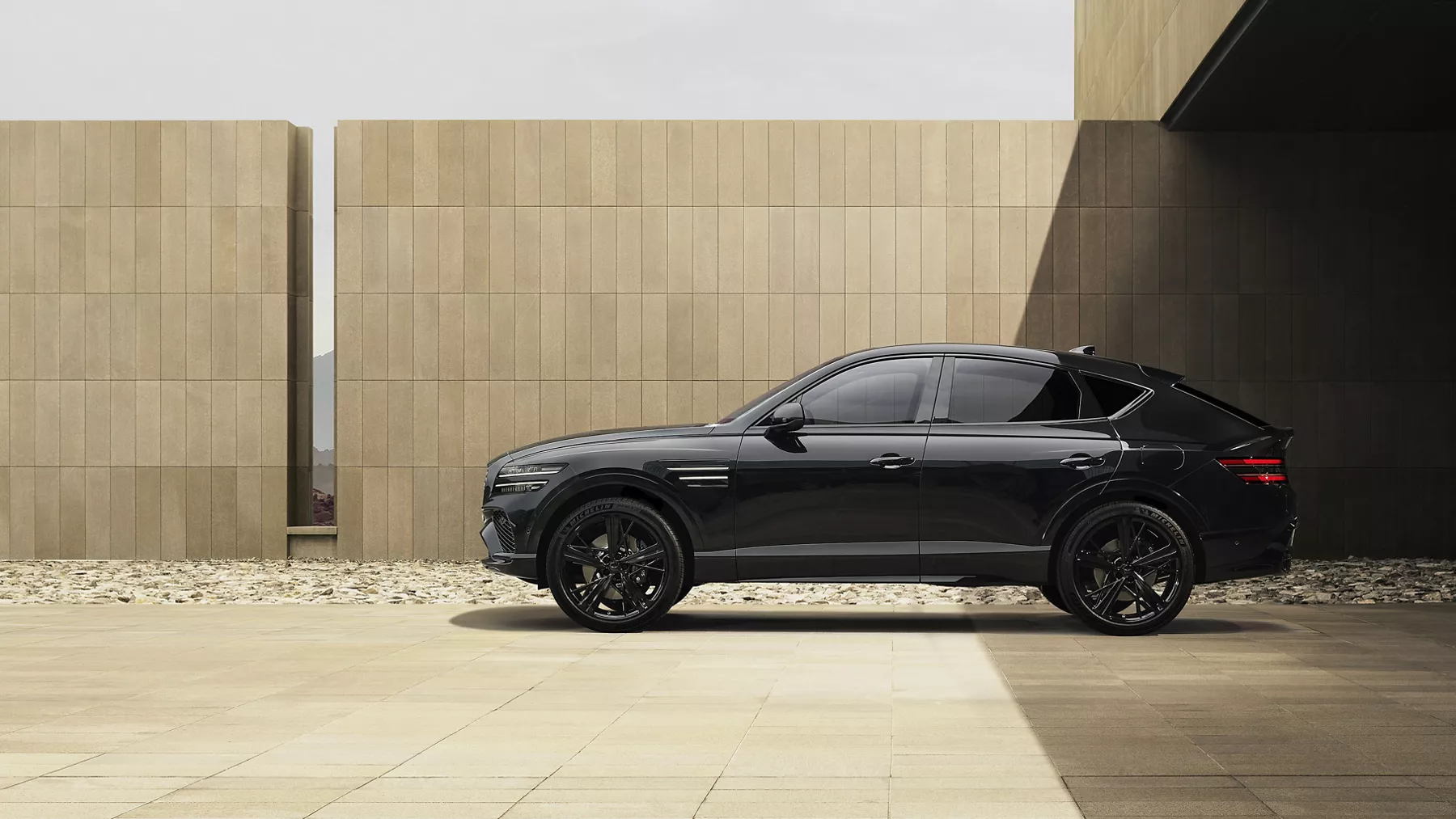 Driver side profile view of 2026 Genesis GV80 Coupe Prestige Black parked outside modern building