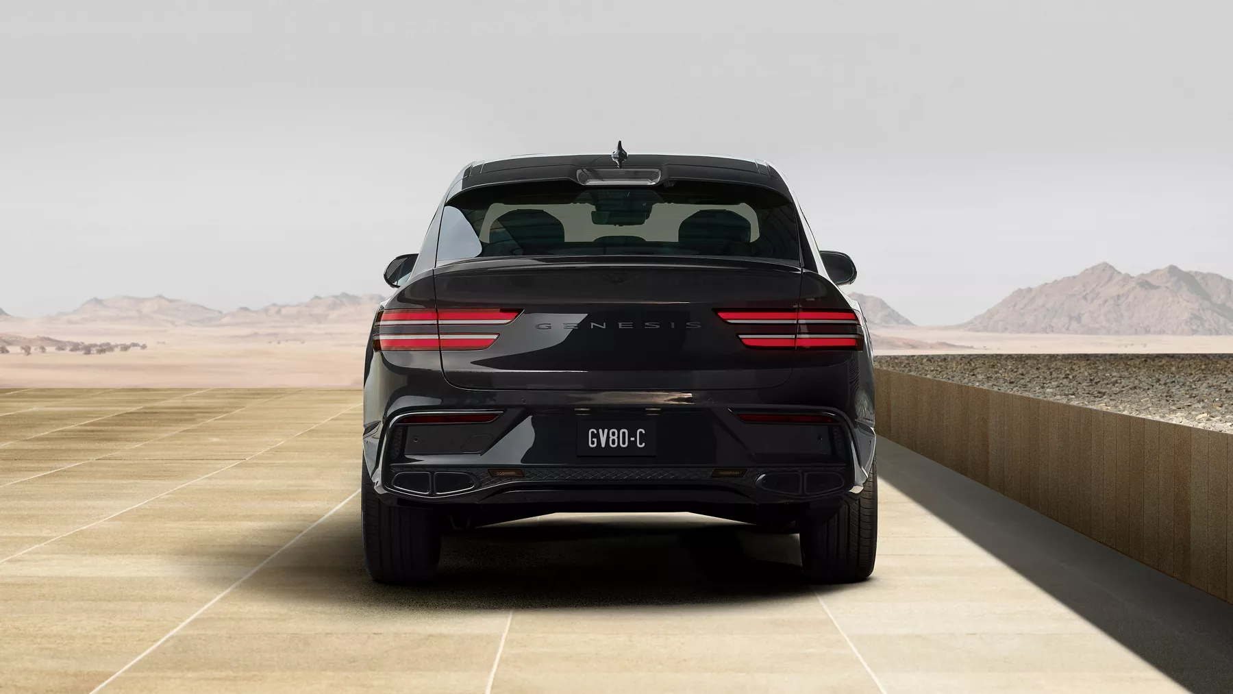 Rear view of Genesis GV80 Coupe Prestige Black outside of concrete modern building in desert