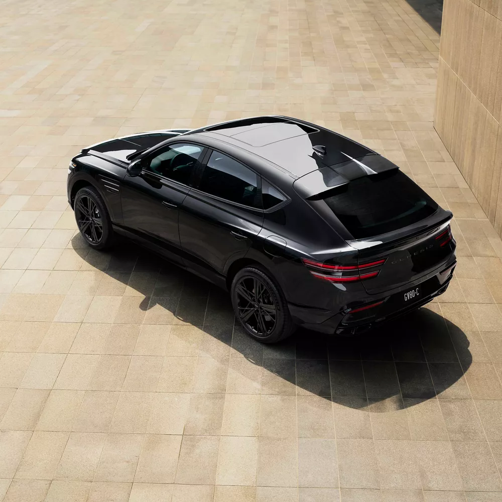 3/4 aerial rear driver side view of Genesis GV80 Coupe Prestige Black parked on concrete surface