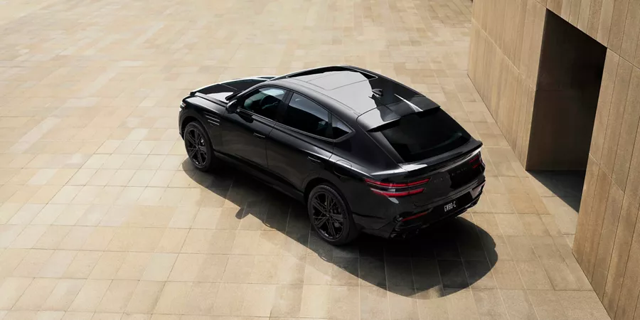 3/4 aerial rear driver side view of Genesis GV80 Coupe Prestige Black parked on concrete surface