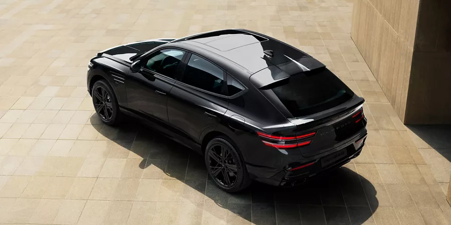 Rear overhead 3/4 view of 2026 Genesis GV80 Coupe Prestige Black parked on beige tiles