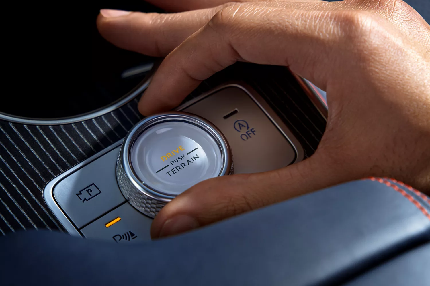 Interior closeup of hand moving the Terrain Mode button on center console inside Genesis GV80 Coupe