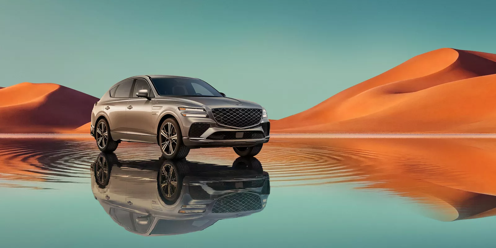 7/8 front passenger view of Savile Silver Genesis GV80 Coupe, blue lake & orange mountain background