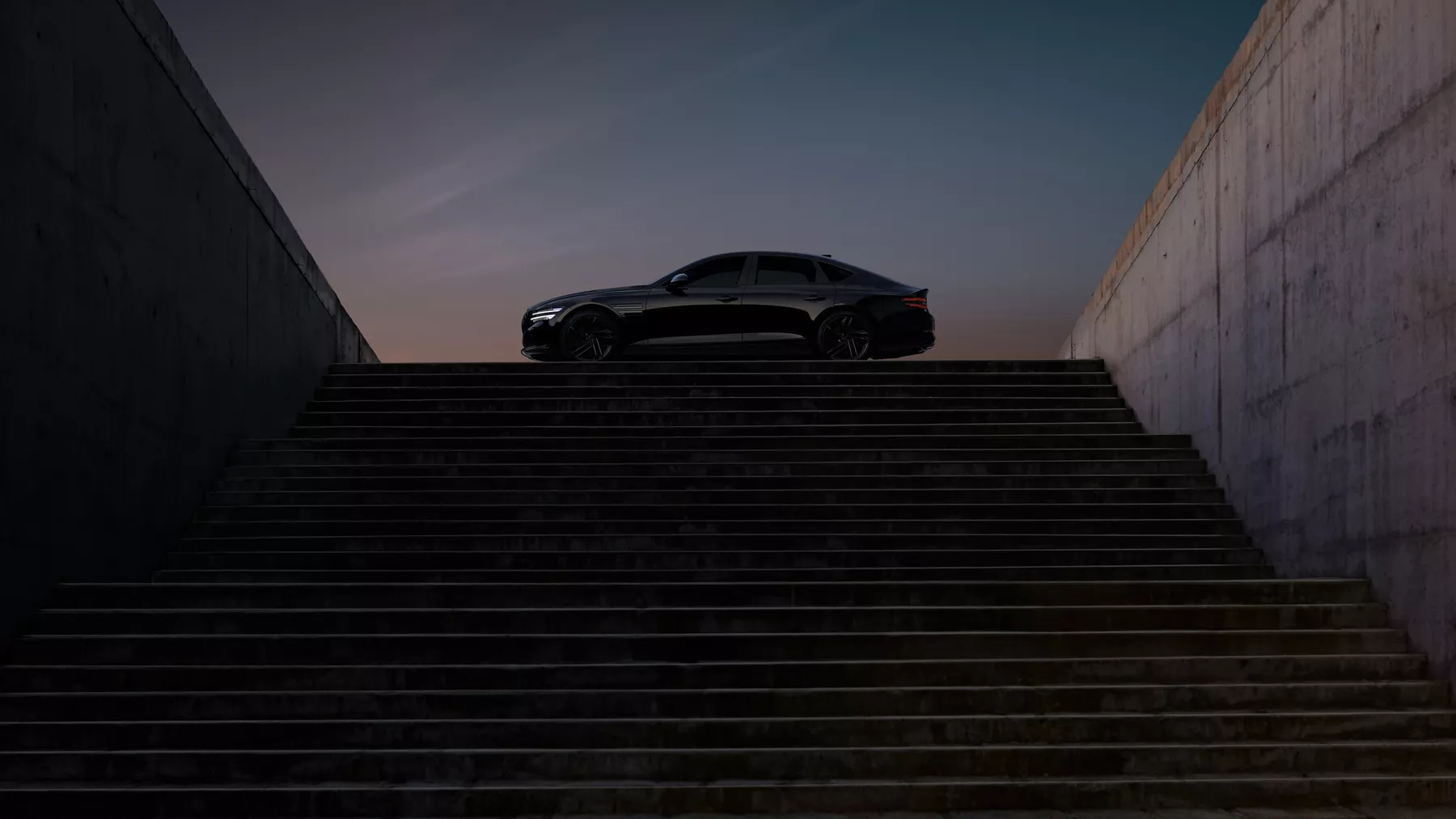 Driver side profile silhouette of Genesis G80 Prestige Black atop stairs of modern building at dusk