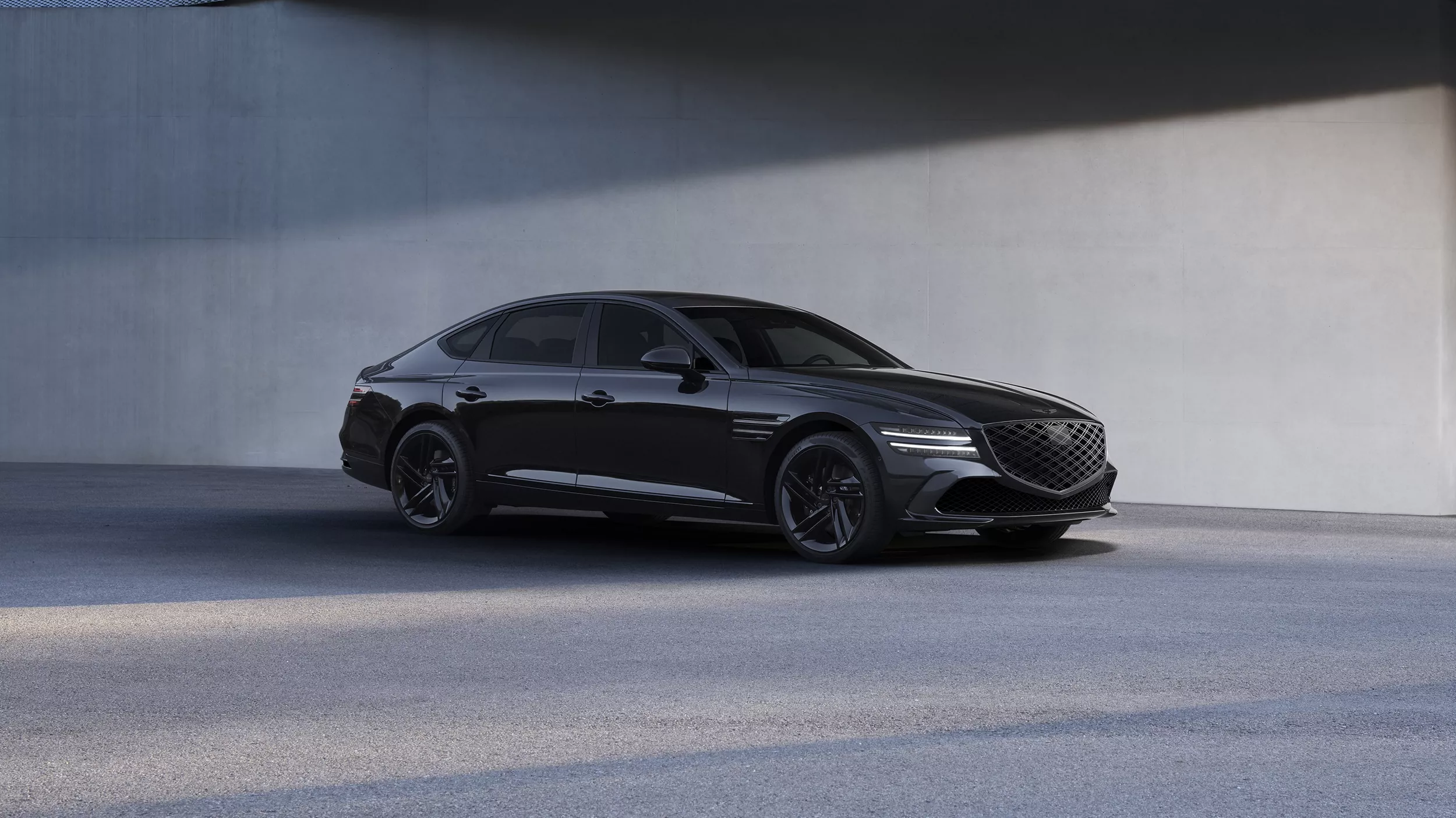 Passenger side profile view of 2026 Genesis G80 Prestige Black in front of a modern cement building