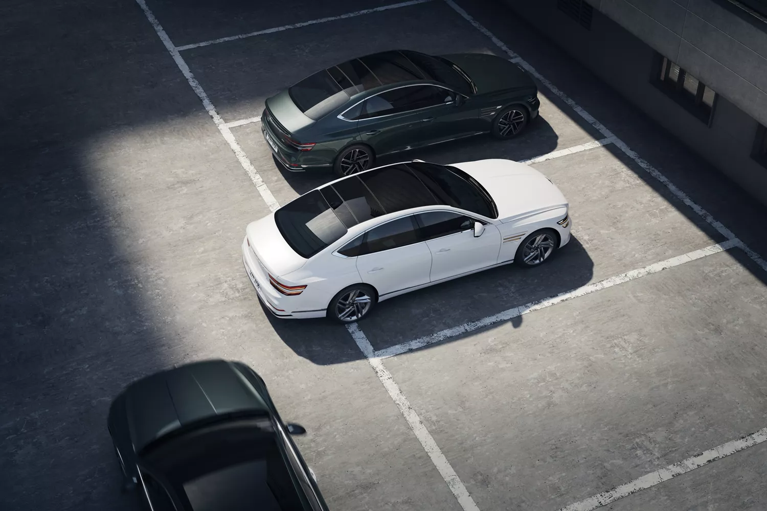 Overhead view of white Genesis G80 parked between two cars in a lot