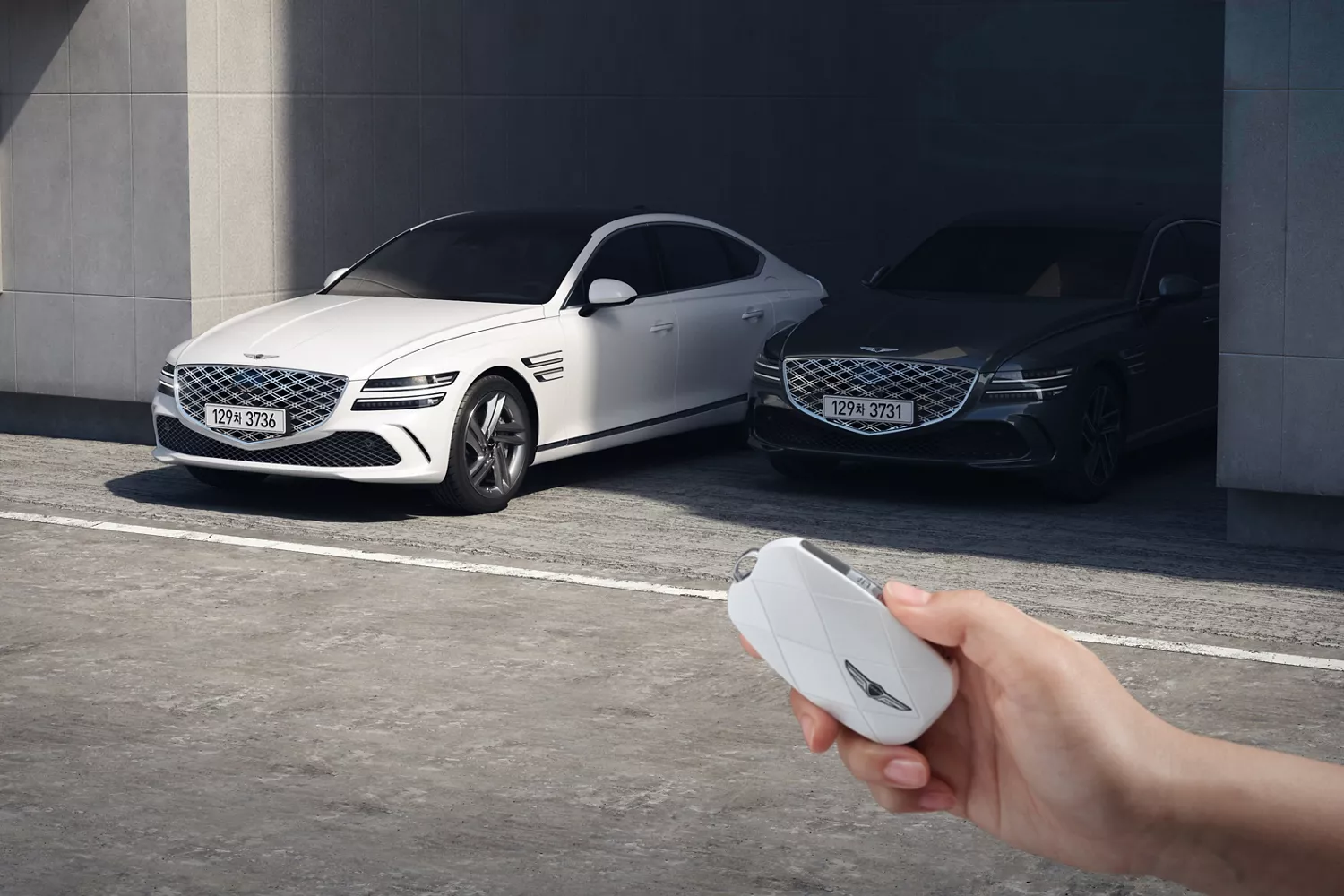 Hand holding white Genesis Key 2 in front of two white and black Genesis G80's parked in carport