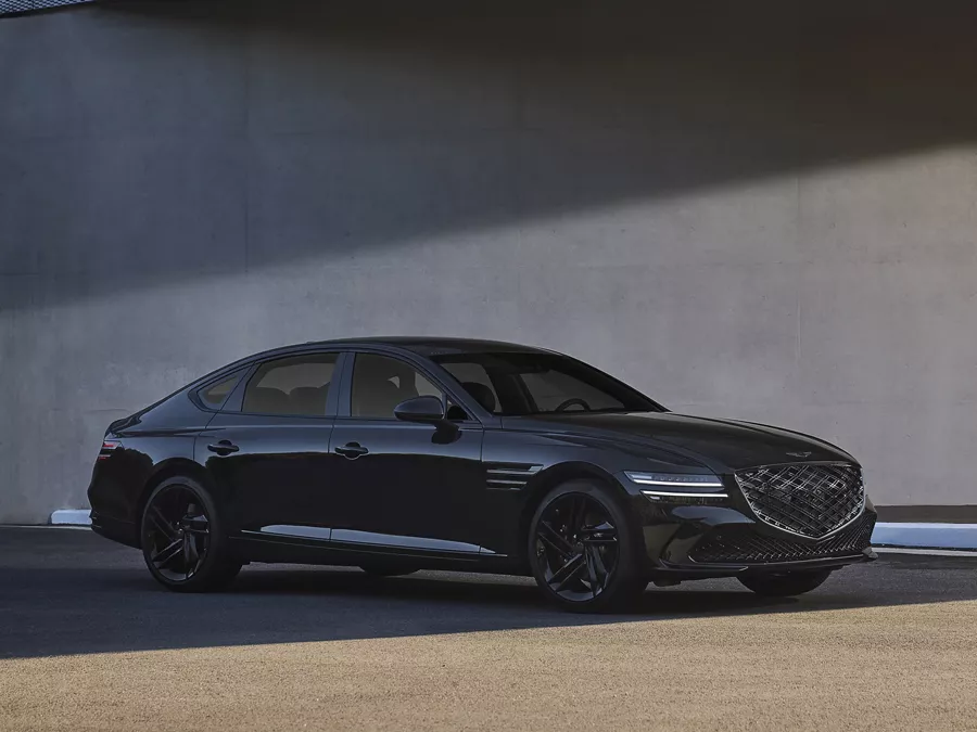 7/8 passenger side view of Genesis G80 Prestige Black parked next to a modern building
