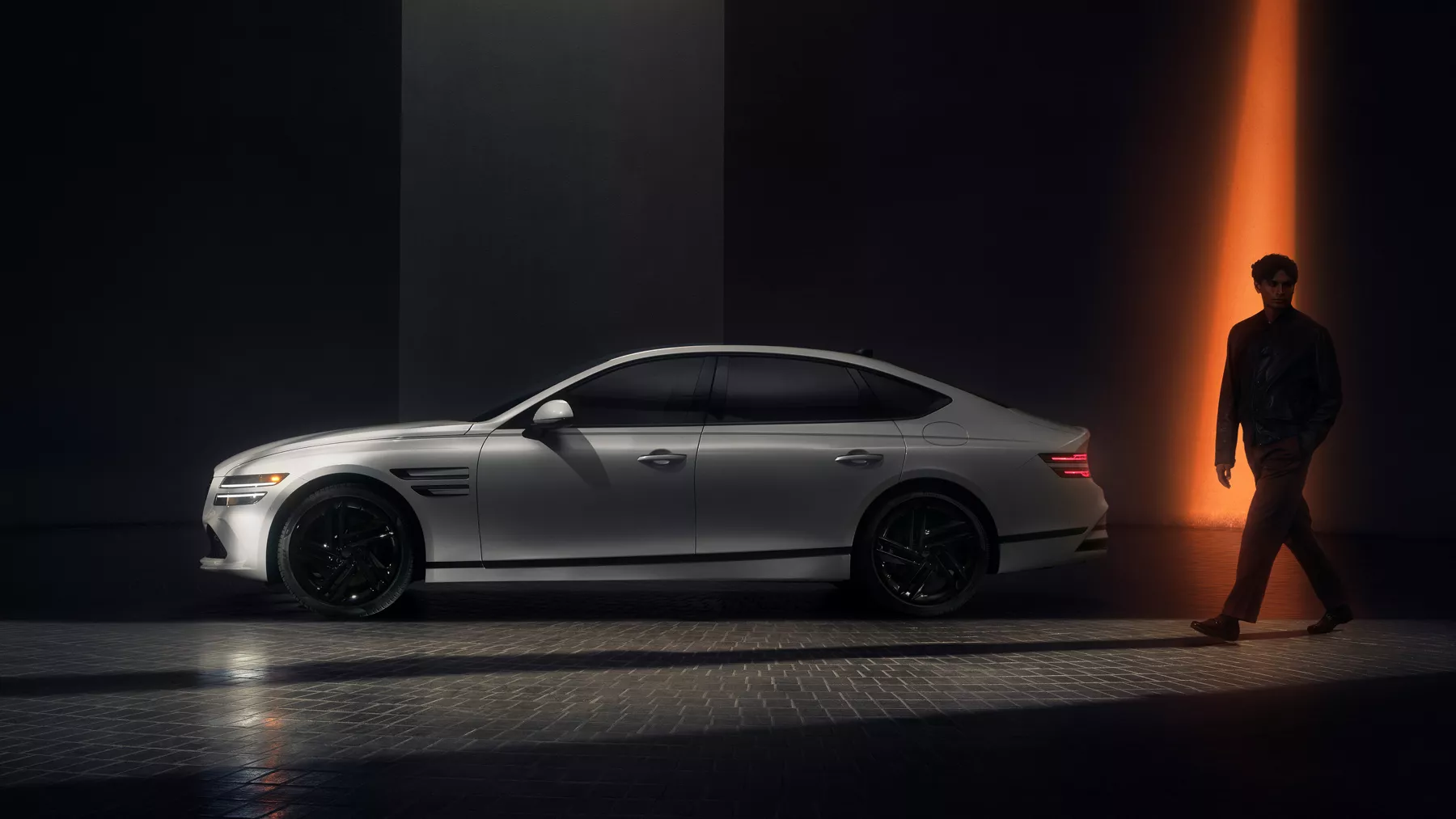 Driver side view of Genesis G80 Prestige Black in Uyuni White, silhouette of human figure behind