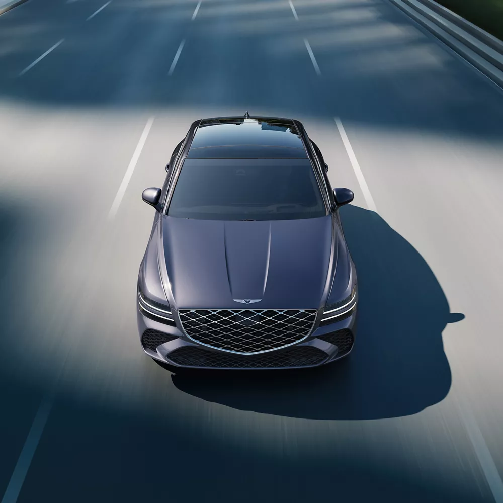Front high angle view of Genesis G80 in Ceres Blue in motion driving on city street