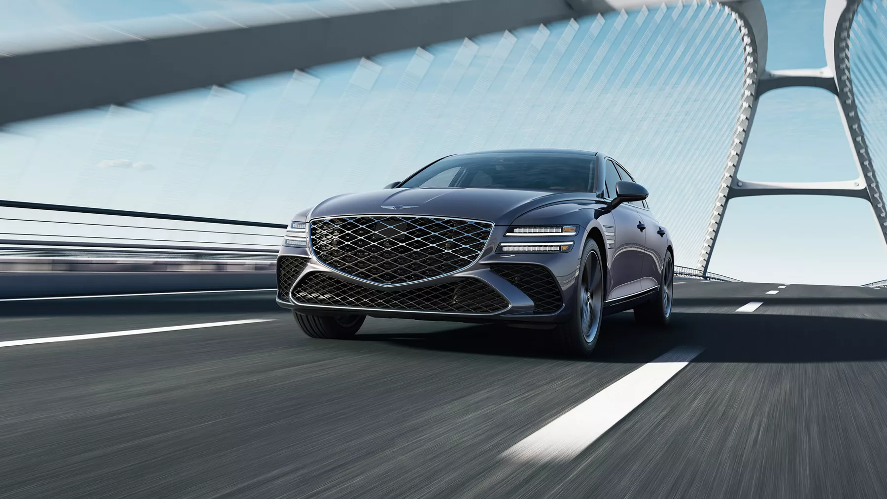 Front low angled view of 2026 Genesis G80 in Ceres Blue driving over modern suspension bridge