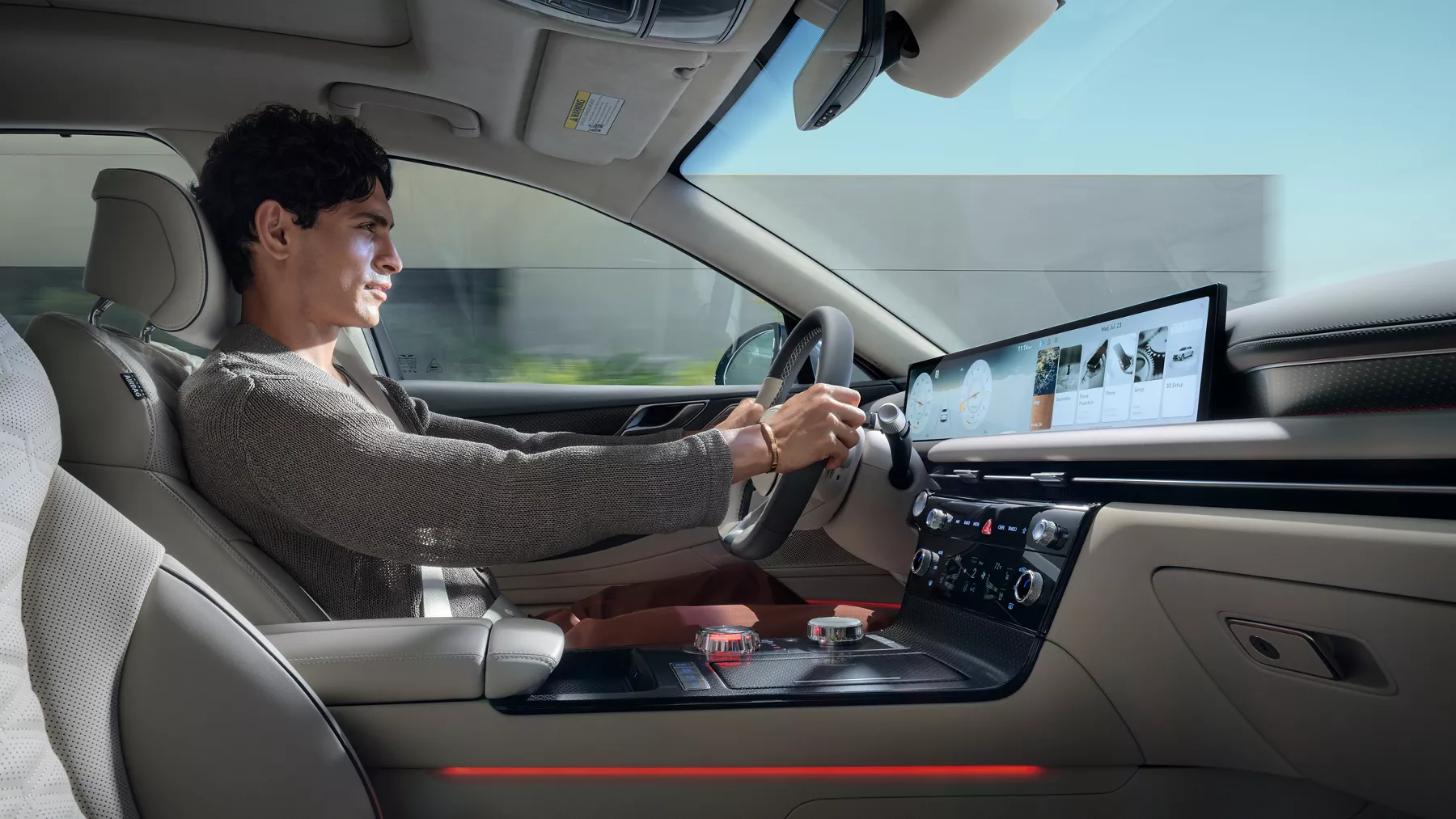 Interior passenger seat view of man driving Genesis G80, blue sky visible through windshield