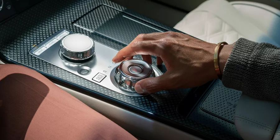 Interior close up of driver's hands on shift by wire gear selector wheel inside the Genesis G80