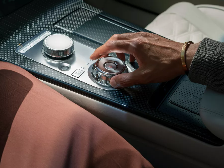 Interior close up of driver's hands on shift by wire gear selector wheel inside the Genesis G80