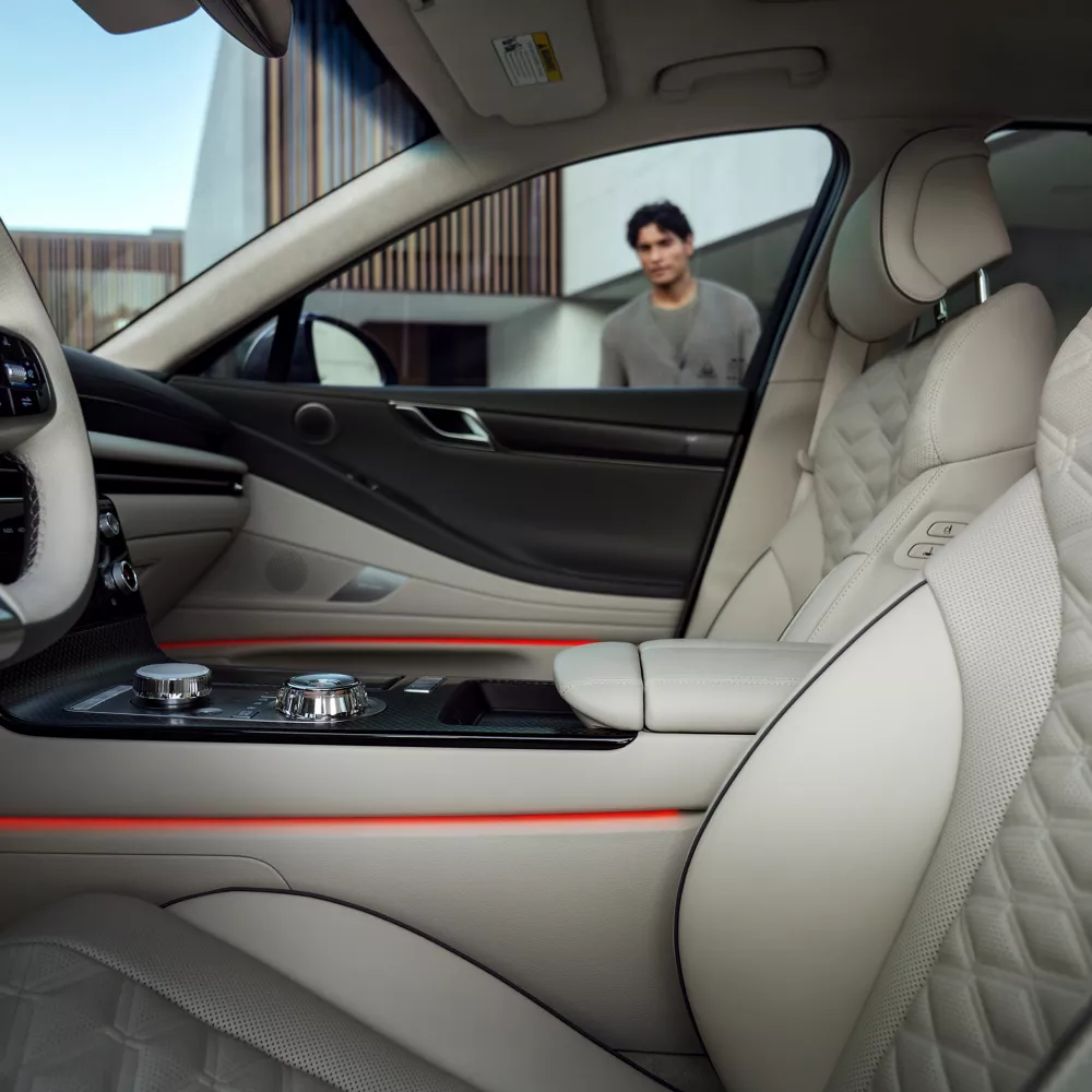 Interior driver side door pov of Genesis G80 cockpit, man looking through passenger side window