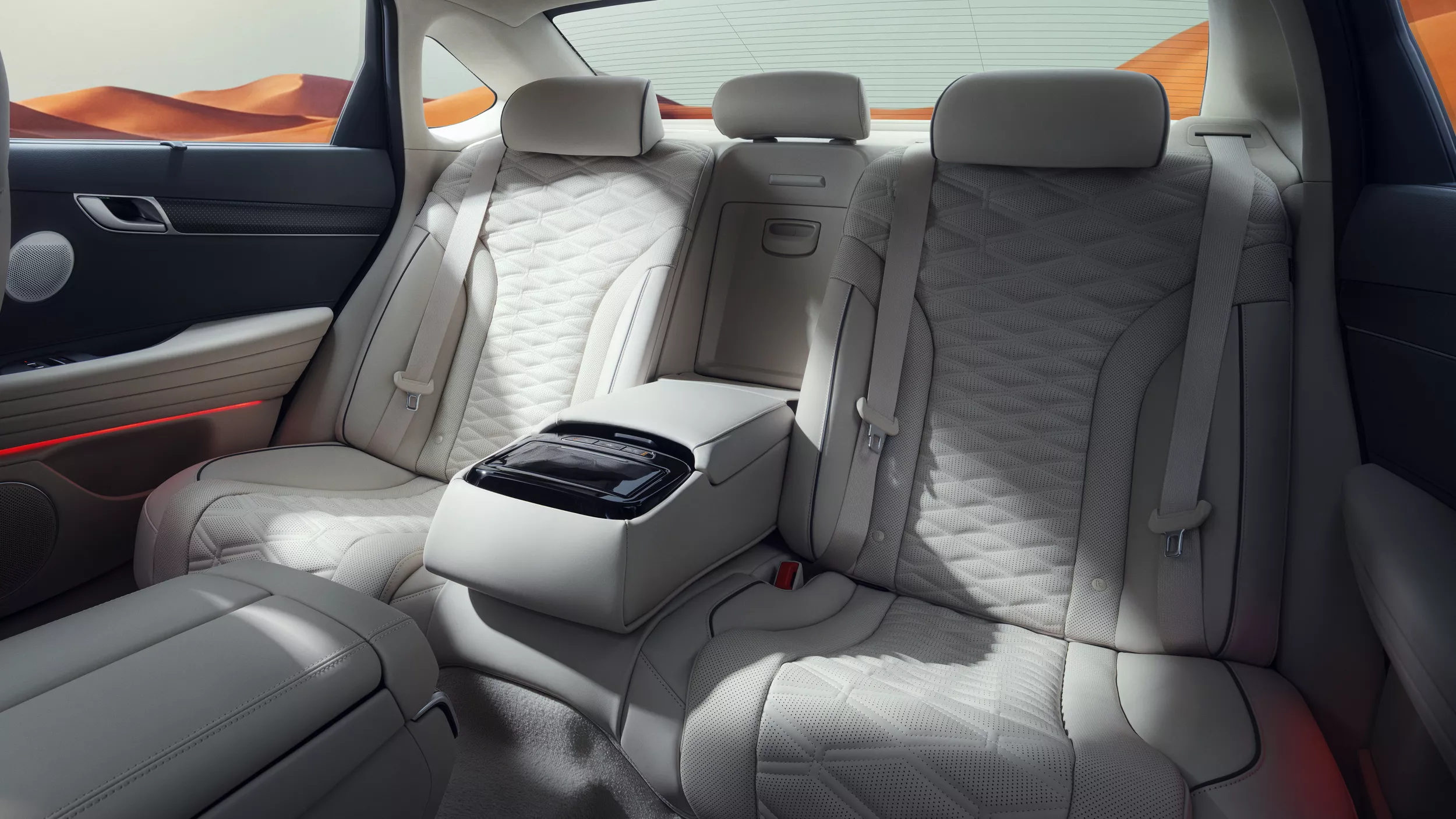 Interior view of gray rear seating inside Genesis G80 with blue sky and mountains in background