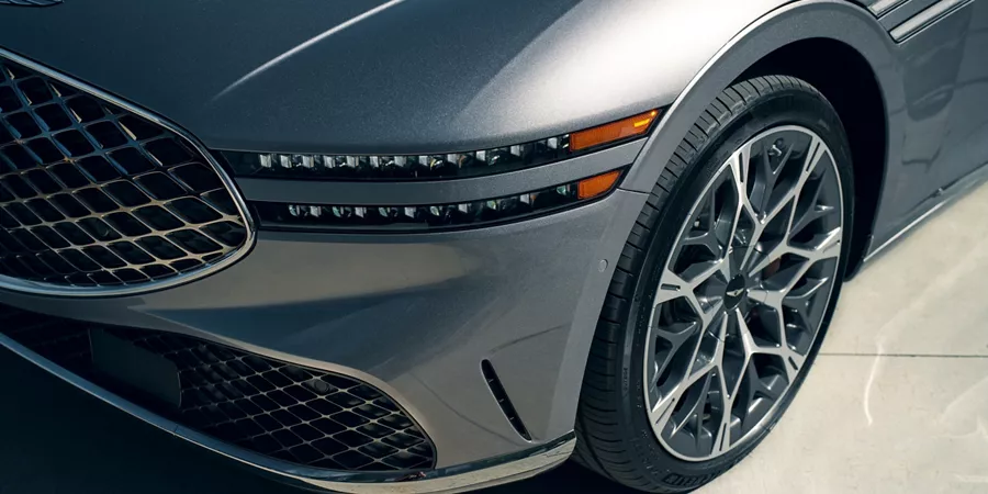 3/4 driver side close up of grille, front headlamp and tire on 2026 Genesis G90 in Savile Silver