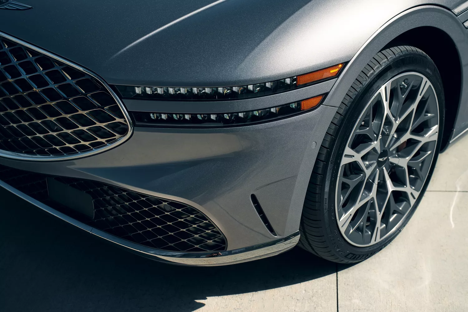 3/4 driver side close up of grille, front headlamp and tire on 2026 Genesis G90 in Savile Silver