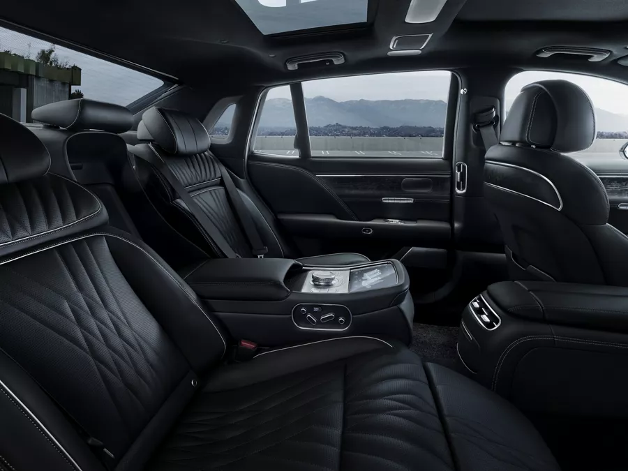 Rear passenger view of 2026 Genesis G90 interior in Black Monotone, with mountains in background