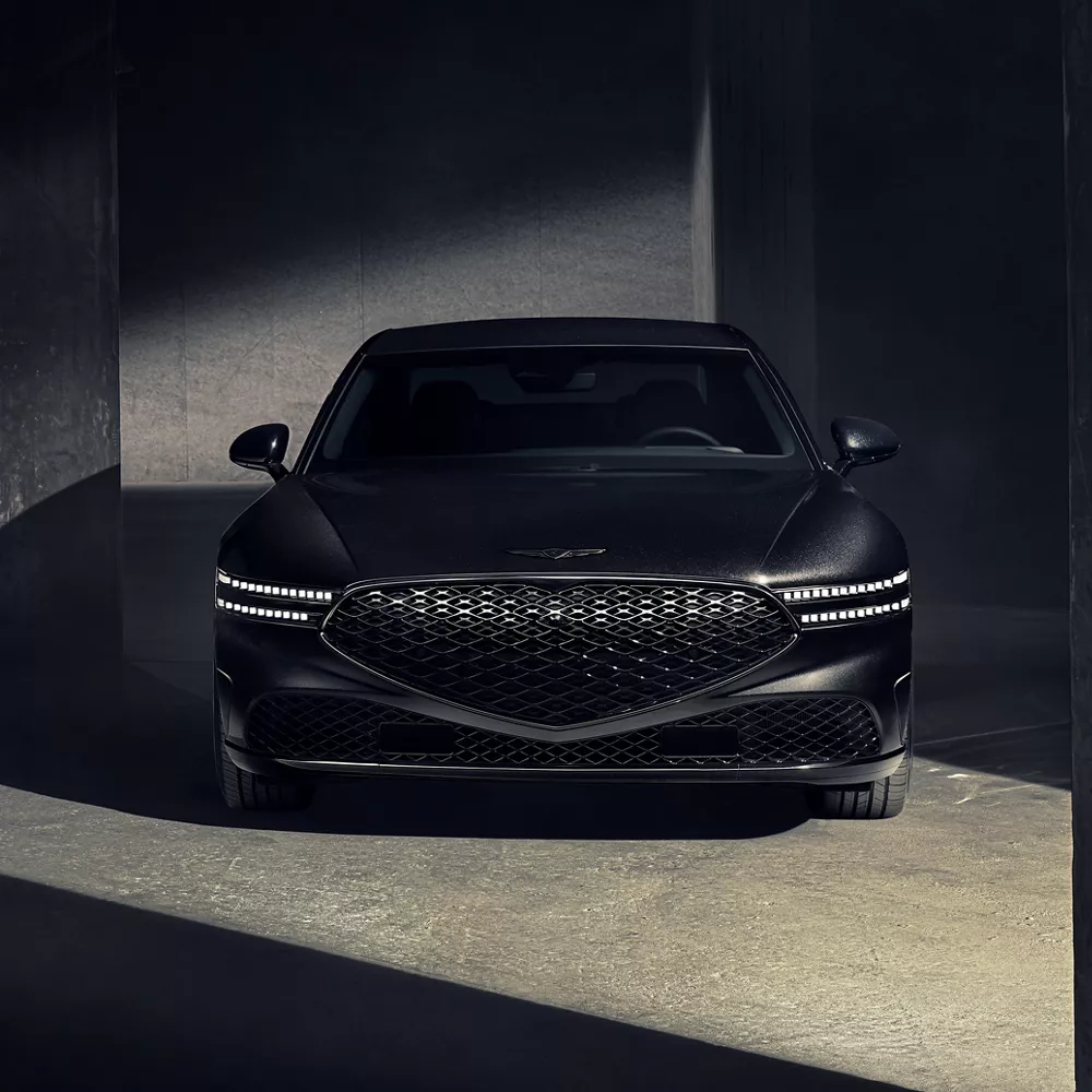 Front angle of 2026 Genesis G90 in Prestige Black parked in a dramatically lit parking garage