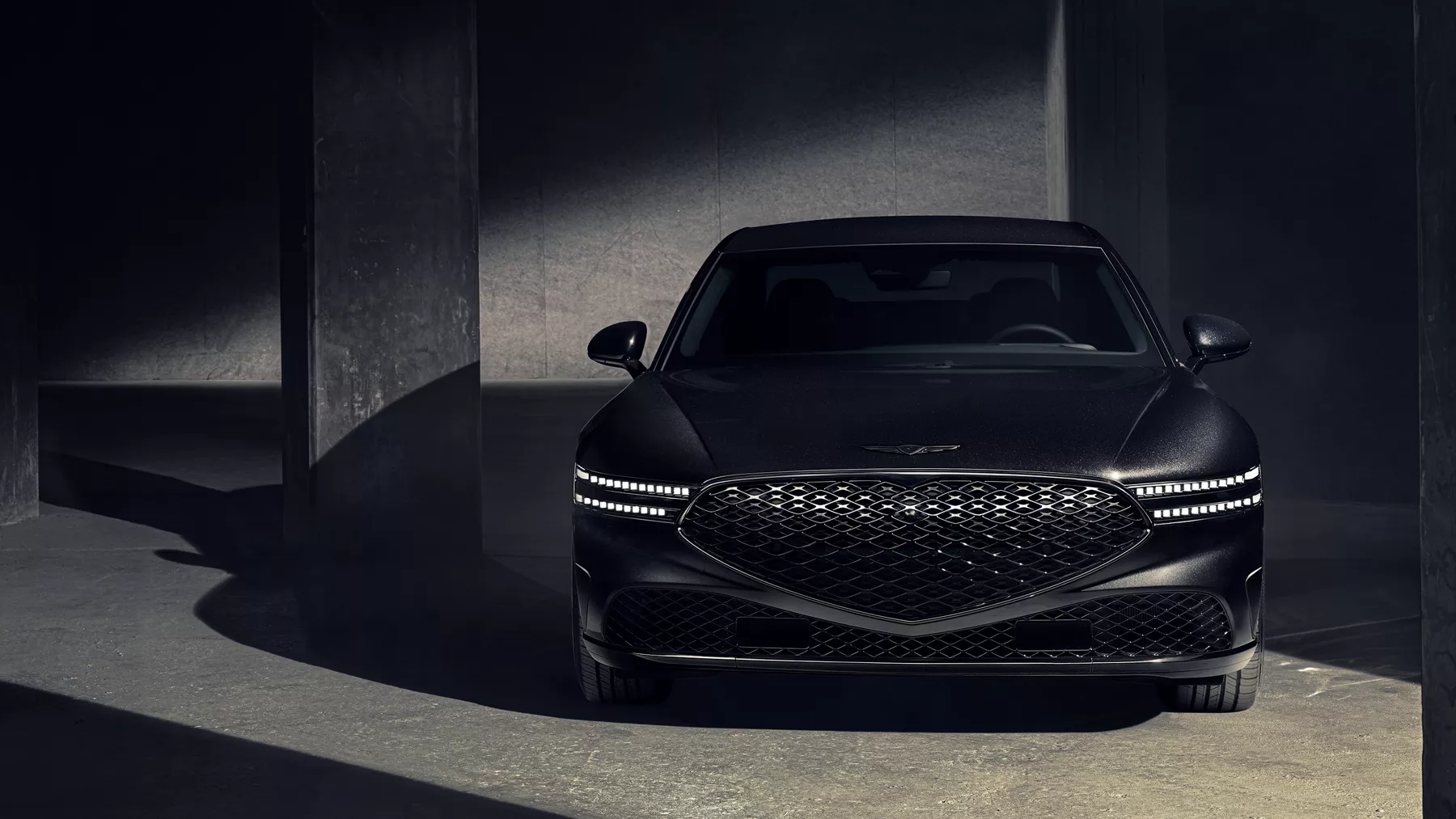 Front angle of 2026 Genesis G90 in Prestige Black parked in a dramatically lit parking garage