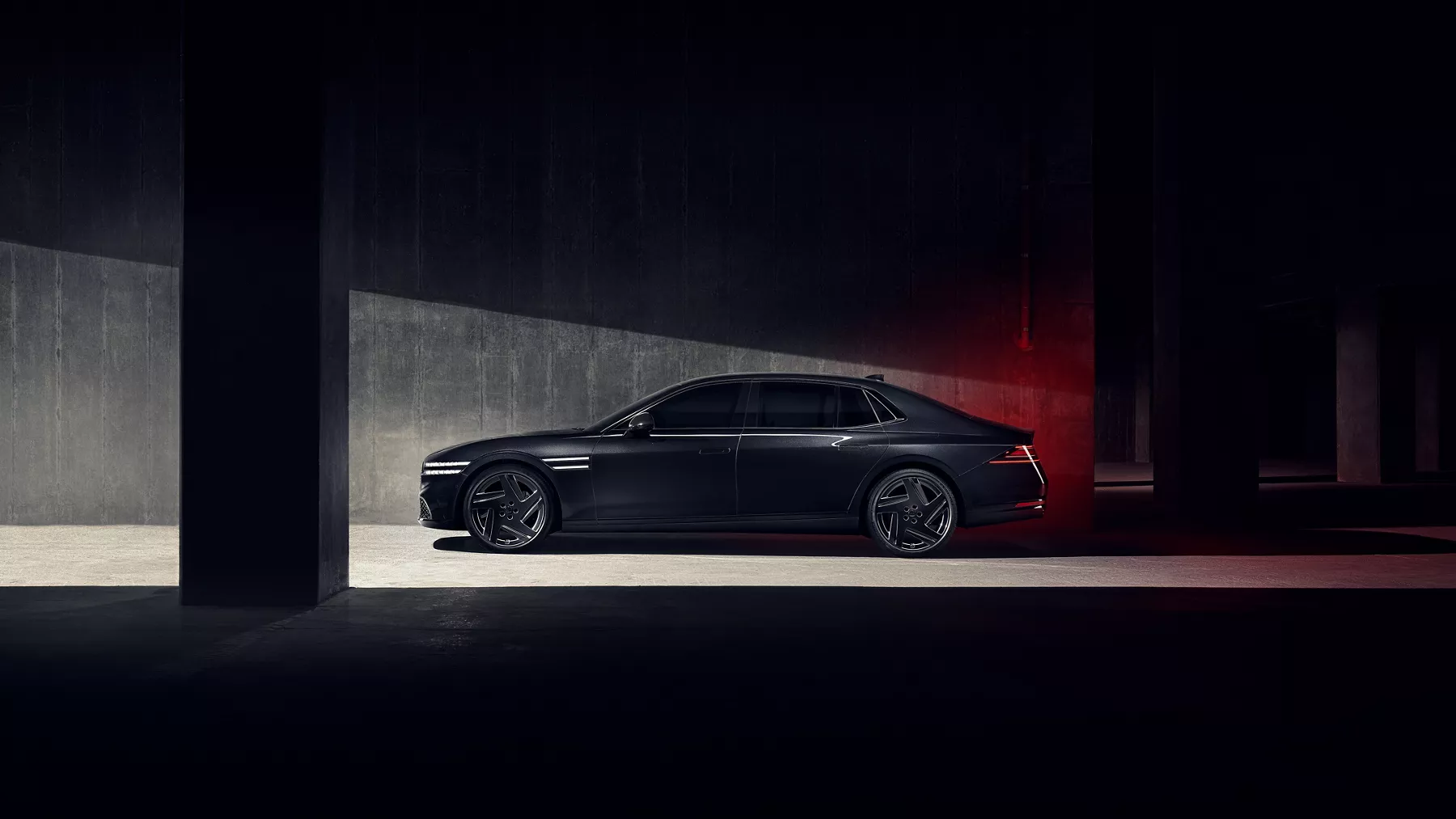 Driver side profile view of 2026 Genesis G90 in Prestige Black parked in a dimly lit parking garage