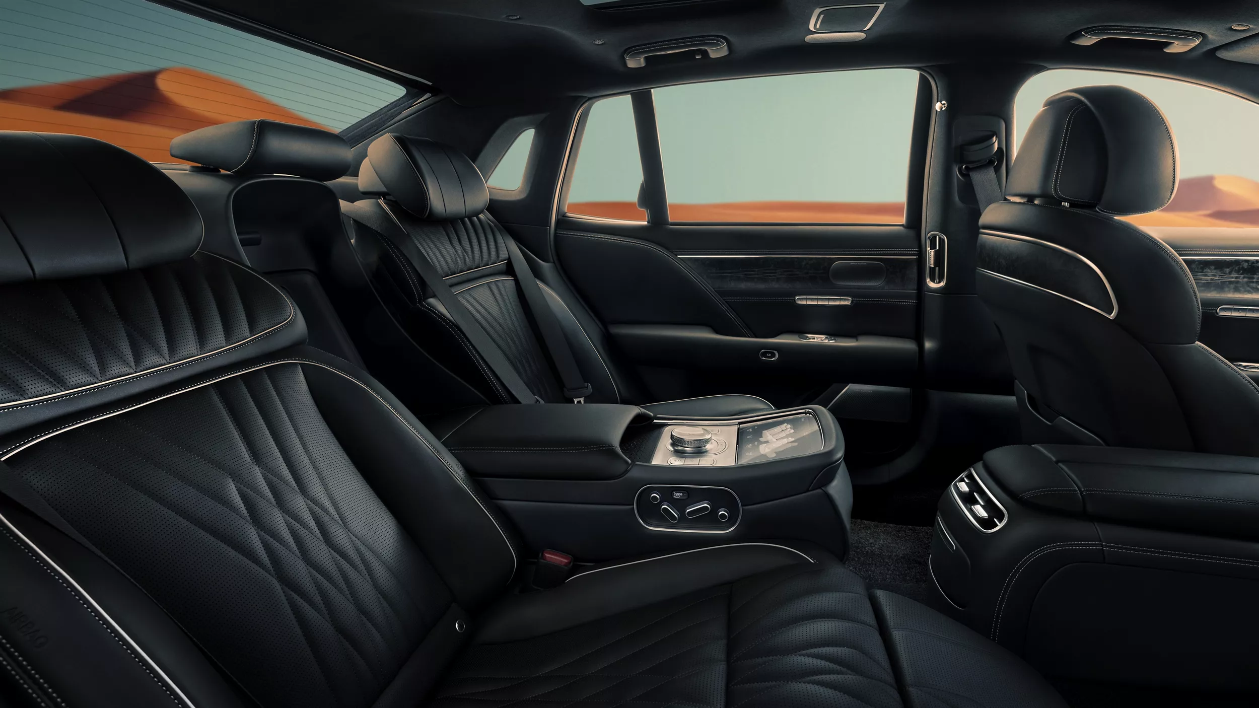 Interior view of black rear seating inside Genesis G90 with blue sky and mountains in background