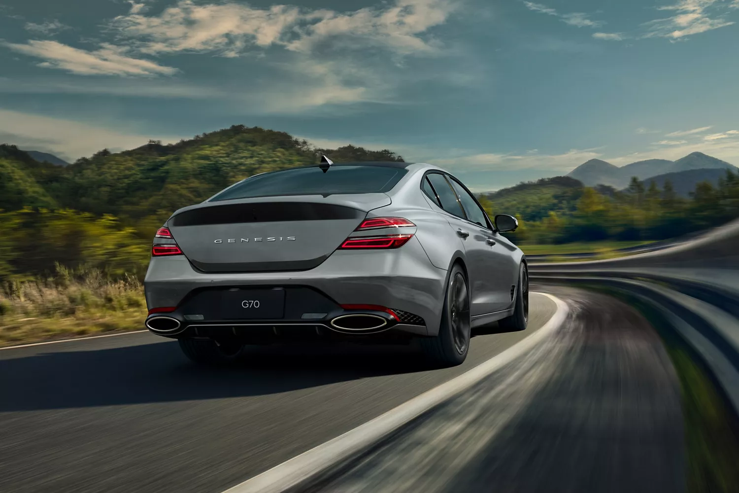 3/4 rear passenger side view of 2027 Genesis G70 in Savile Silver driving on mountainous highway