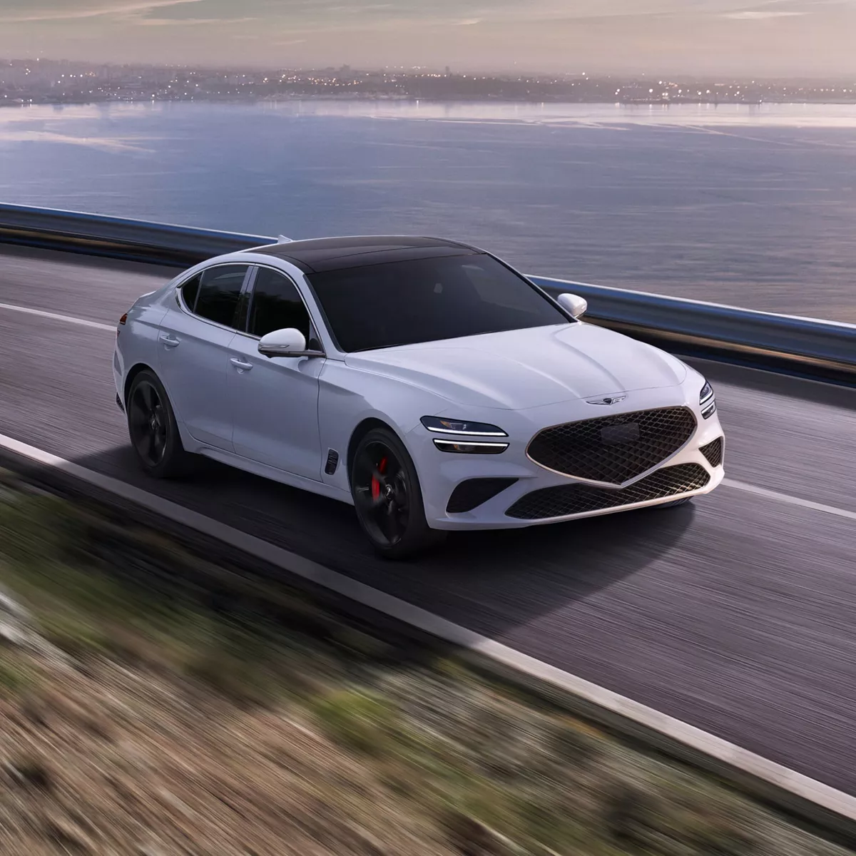 3/4 front passenger side view of 2027 Genesis G70 in Uyuni White driving along a coastal highway