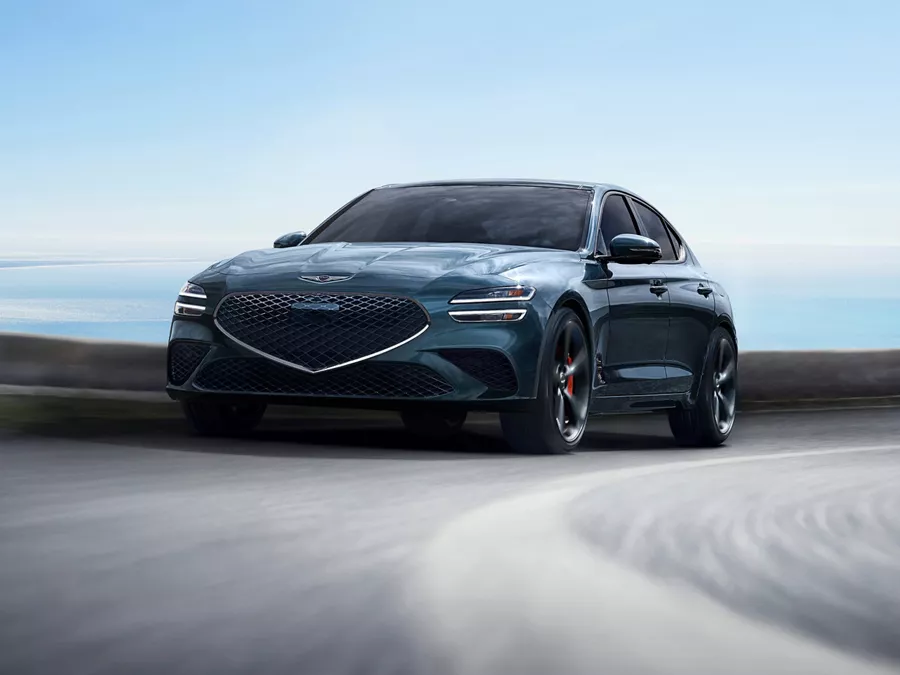 3/4 front driver side view of 2027 Genesis G70 in Tasman Blue in motion driving on a track