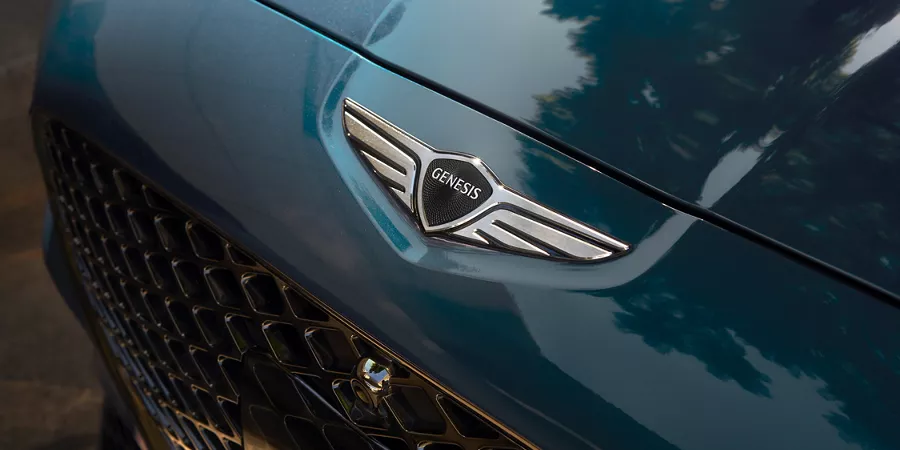 Overhead close up of Genesis logo hood emblem on 2027 Genesis G70 in Tasman Blue