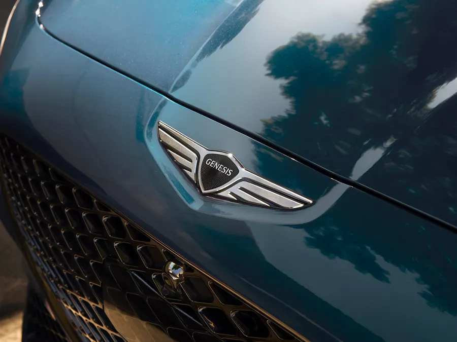 Overhead close up of Genesis logo hood emblem on 2027 Genesis G70 in Tasman Blue