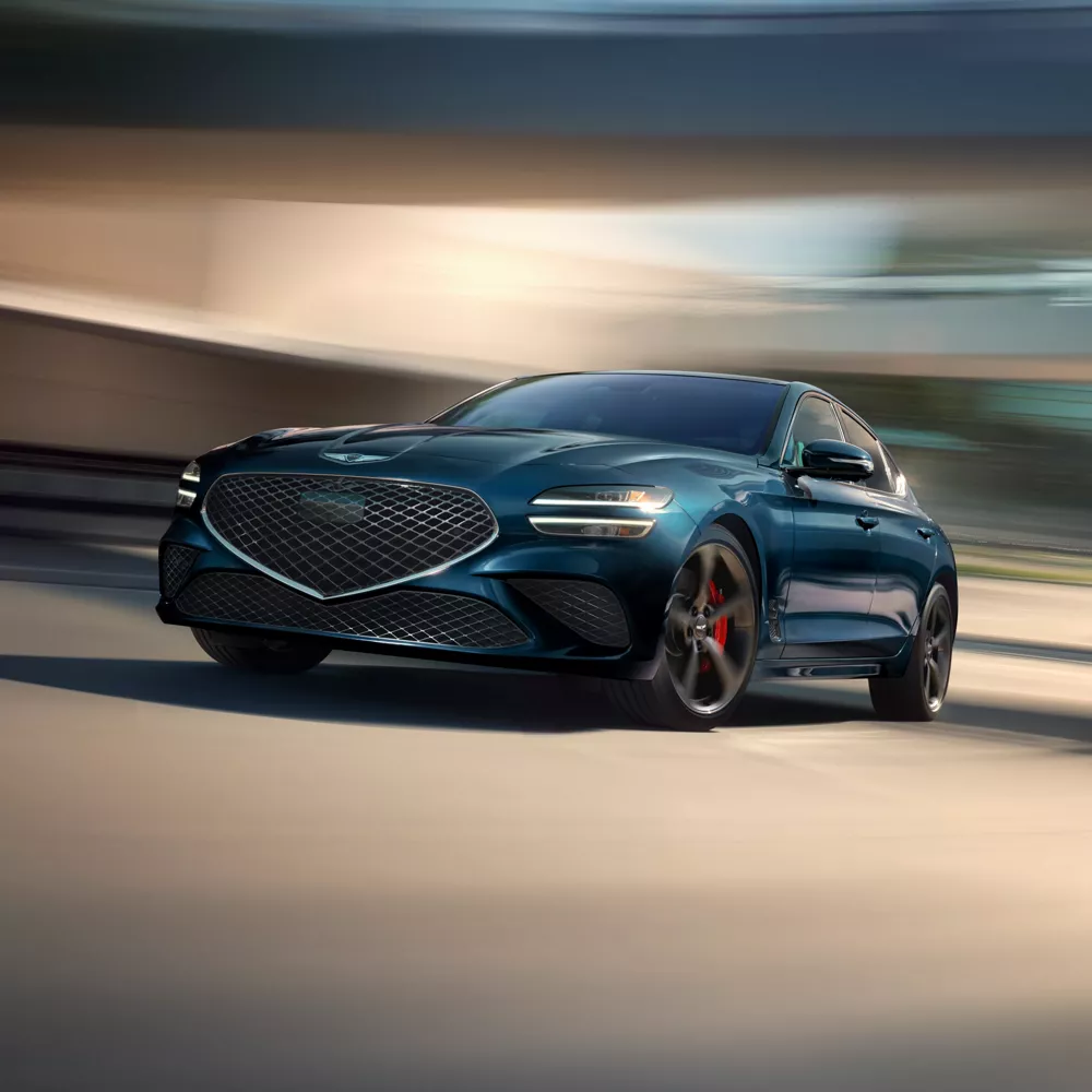 3/4 front driver side view of 2027 Genesis G70 in Tasman Blue against motion blurred background
