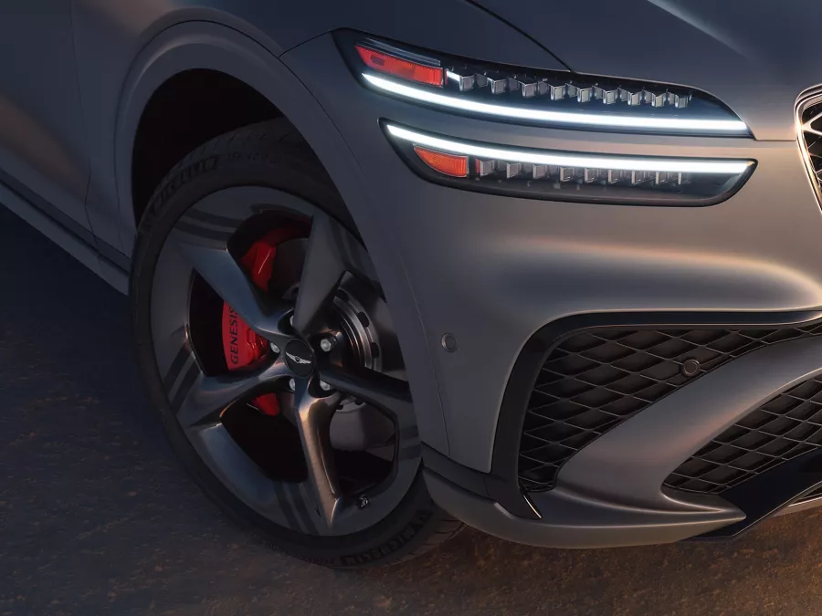 3/4 front passenger side close up of headlight and wheel on Genesis GV70 in Ceres Blue Matte